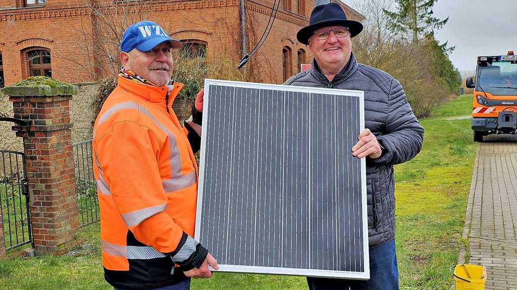 Bauhofmitarbeiter Rüdiger Petrasch (links) und Ortsbürgermeister Tino Bauer beim Anbringen des Solarpanels einer Geschwindigkeitsanzeige.