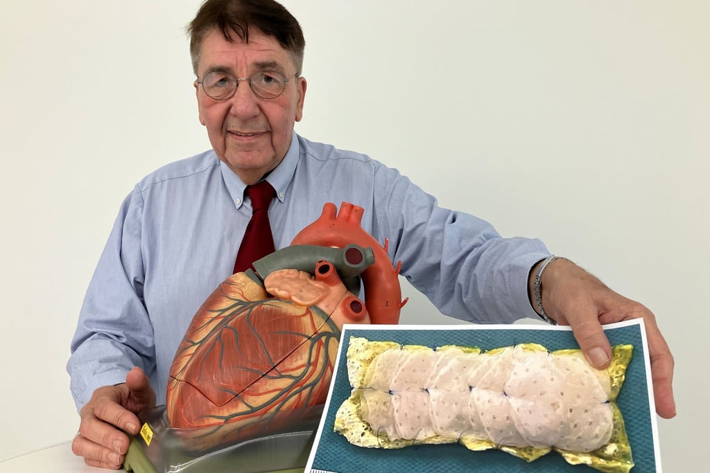 Patient Frank Teege steht neben einem Herz-Modell und zeigt ein Bild eines Herzpflasters.