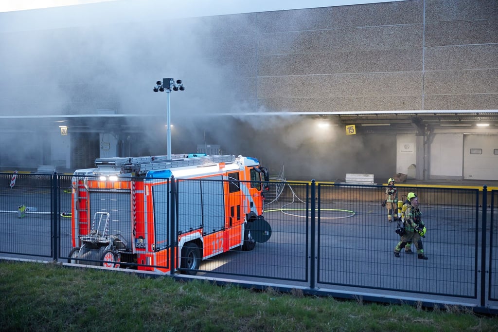 Feuerwehrkräfte sind dabei ein Feuer in einer Lagerhalle zu löschen.
