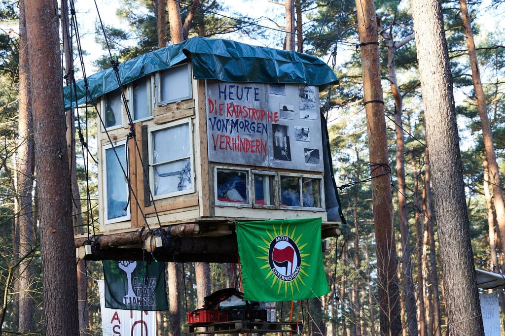 Ein Transparent mit der Aufschrift „Heute die Katastrophe von morgen verhindern“ ist am frühen Morgen in einem Camp der Initiative „Tesla stoppen“ in einem Kiefernwald nahe der Tesla-Gigafactory Berlin-Brandenburg zu sehen.
