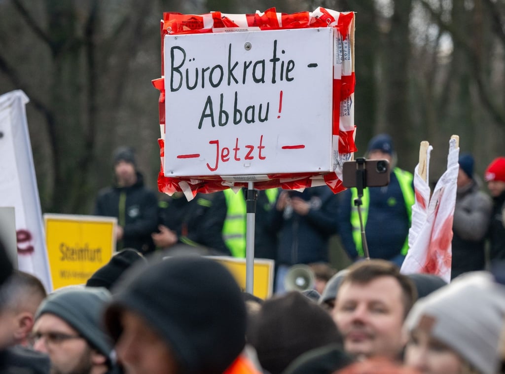 Ein Landwirt hält während der Kundgebung vor dem Brandenburger Tor ein Schild mit der Aufschrift „Bürokratie-Abbau! Jetzt“ hoch.