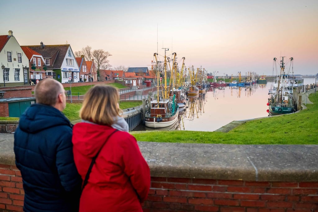 Touristen schauen auf die Krabbenkutter am Hafen.