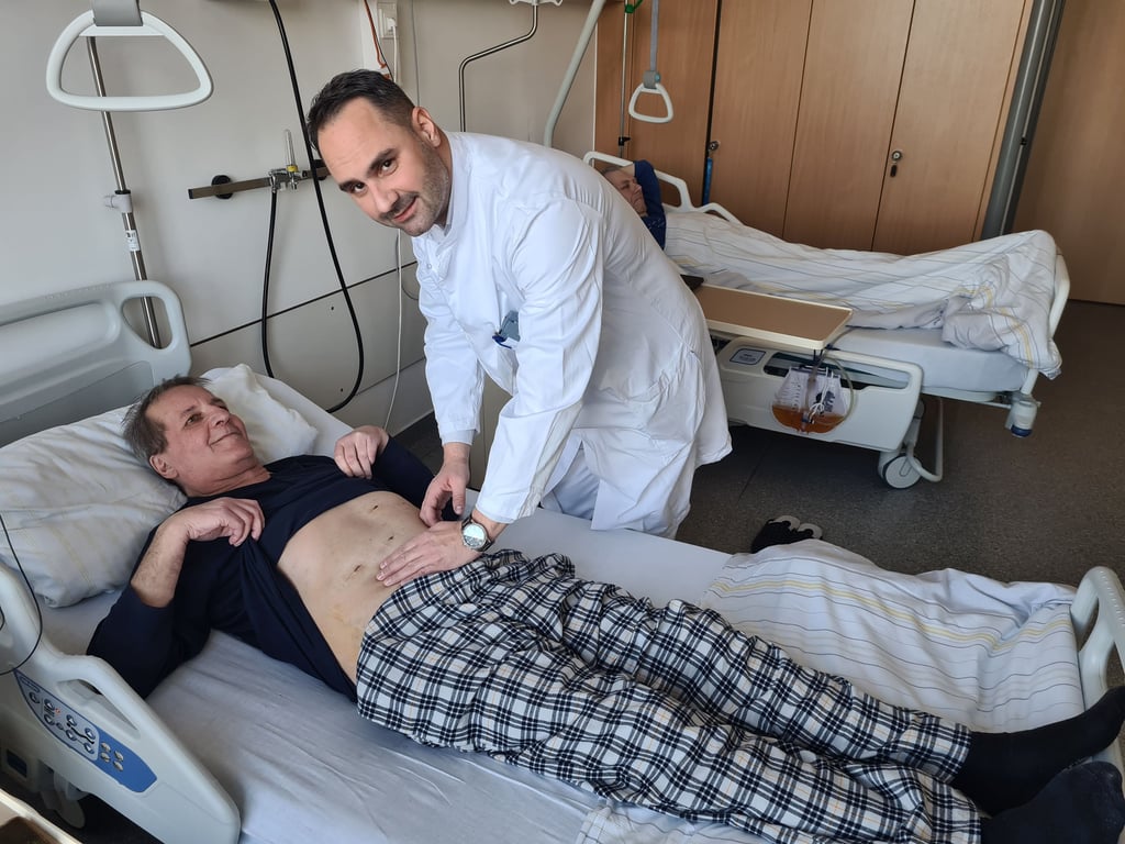Oberarzt Dr. Mihailo Andrić am Bett von Maik Janke nach dessen Darmkrebsoperation.