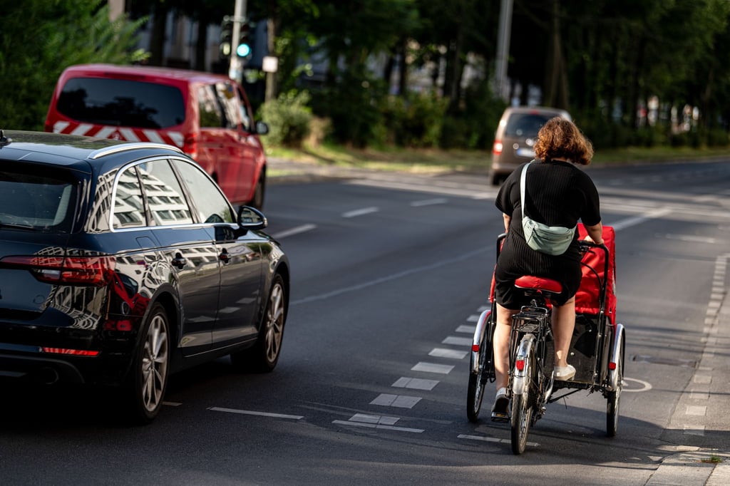 Eine Fahrradfahrerin fährt mit einem Lastenfahrrad. Diese werden oft für den Transport von Kindern benutzt.