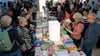 Besucherinnen und Besucher der Leipziger Buchmesse schauen sich einen Bücherstand an.