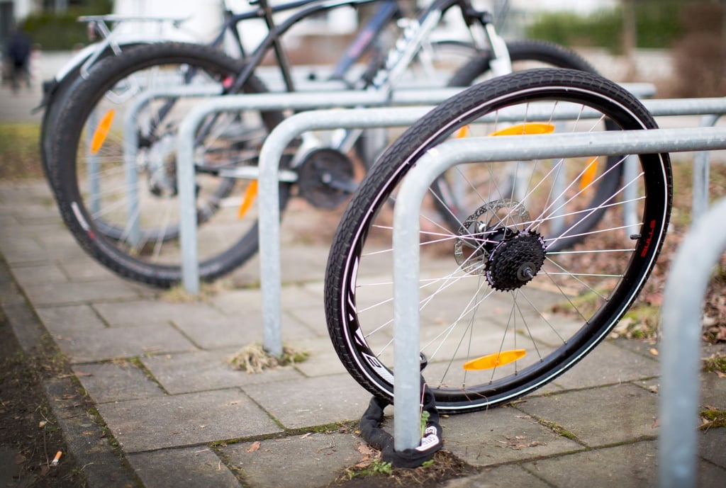 Ein Fahrradreifen ist an einem Fahrradständer angekettet.