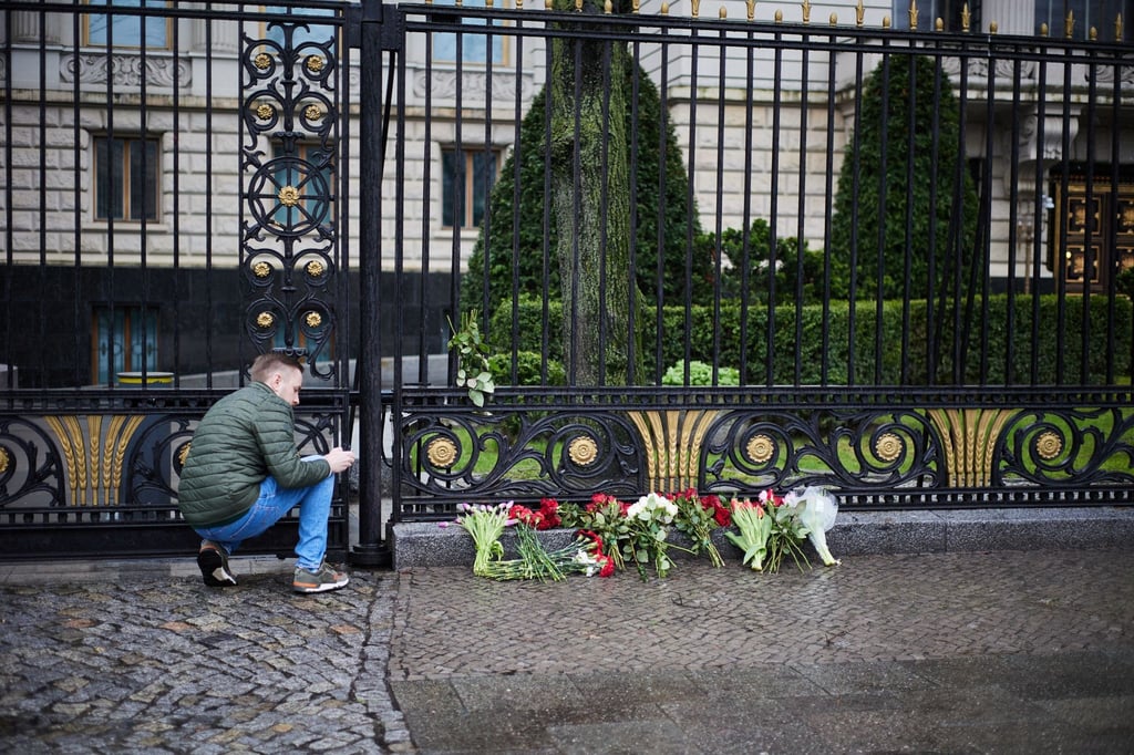 Ilja Roschkow, Pressesprecher der Russischen Botschaft, macht Fotos von Blumen am Zaun der Russischen Botschaft, die nach dem Anschlag in Moskau dort abgelegt wurden.