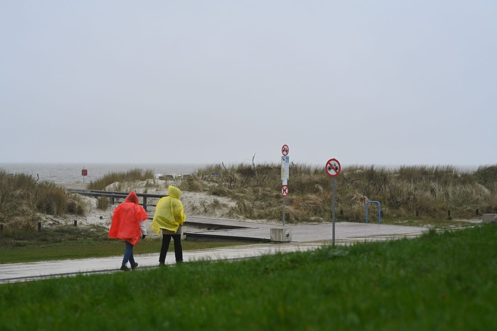 Zwei Tagesgäste laufen bei nassem Wetter in Regenjacken an der Starndpromenade entlang.