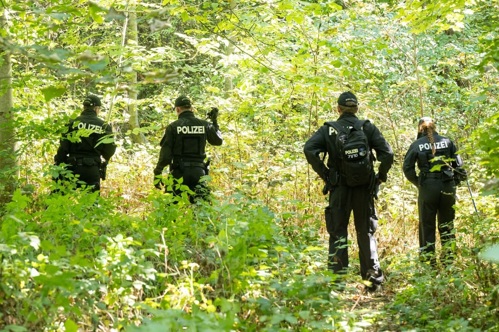 Polizisten durchsuchen ein Waldstück nach Spuren und Gegenständen.