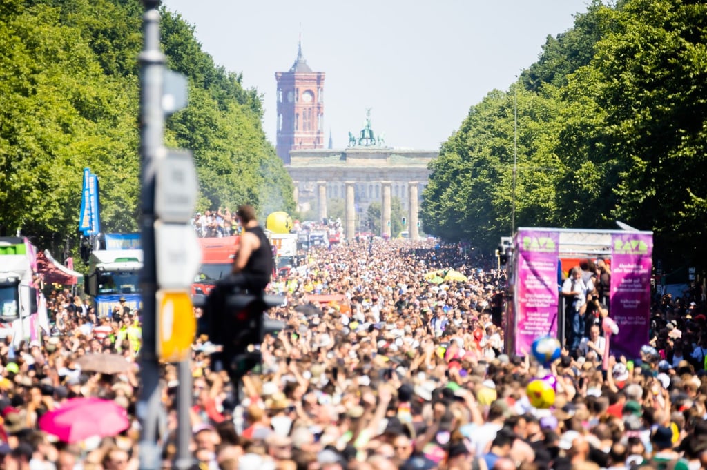 Menschen feiern bei der Technoparade „Rave the Planet“ auf der Straße des 17. Juni vor dem Brandenburger Tor.