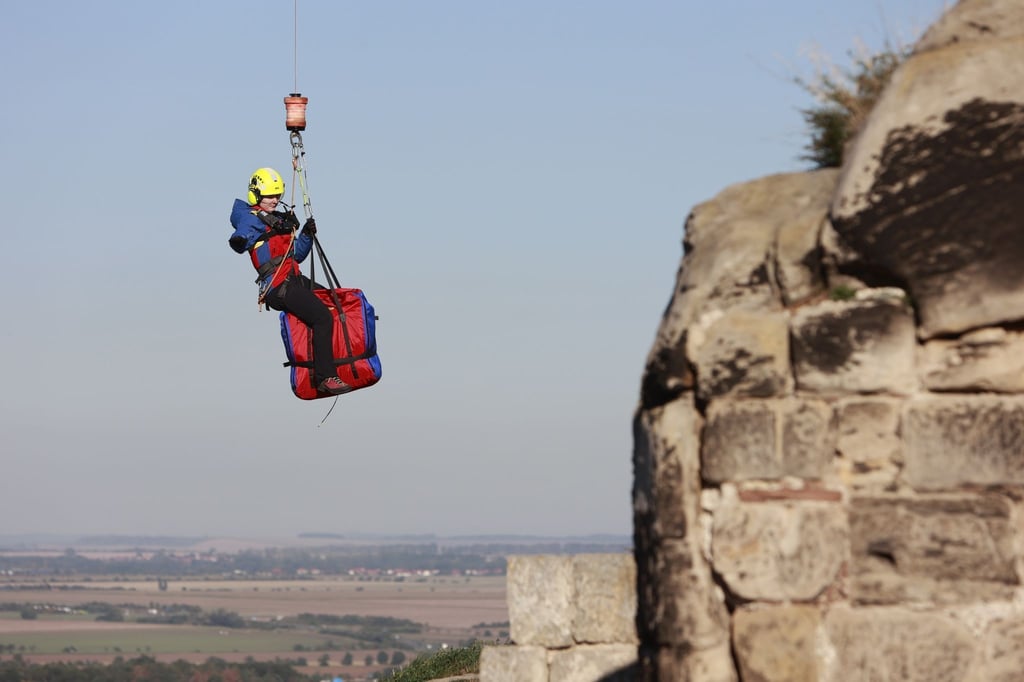 Einsatzkräfte der Bergwacht werden aus einem Hubschrauber der Polizei Sachsen-Anhalt am Regenstein in Blankenburg mit einer Seilwinde herabgelassen.