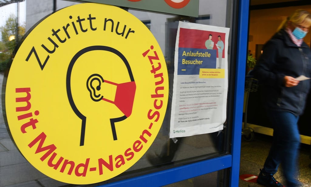 Ein großes Schild weist neben einem Eingang zu einer Klinik in Leipzig auf die Maskenpflicht hin.