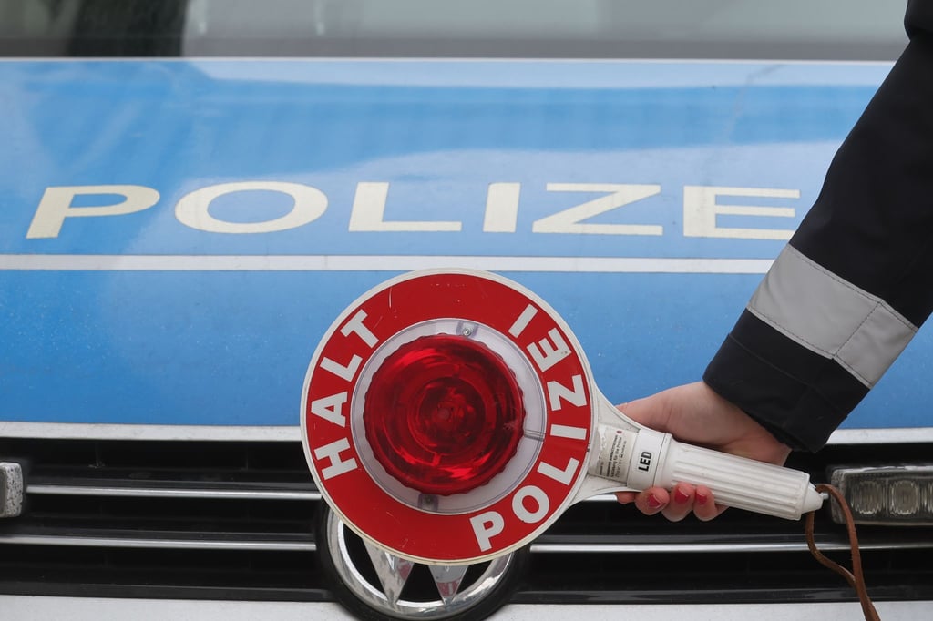 Eine Anhaltekelle vor einem Dienstauto der Thüringer Polizei.