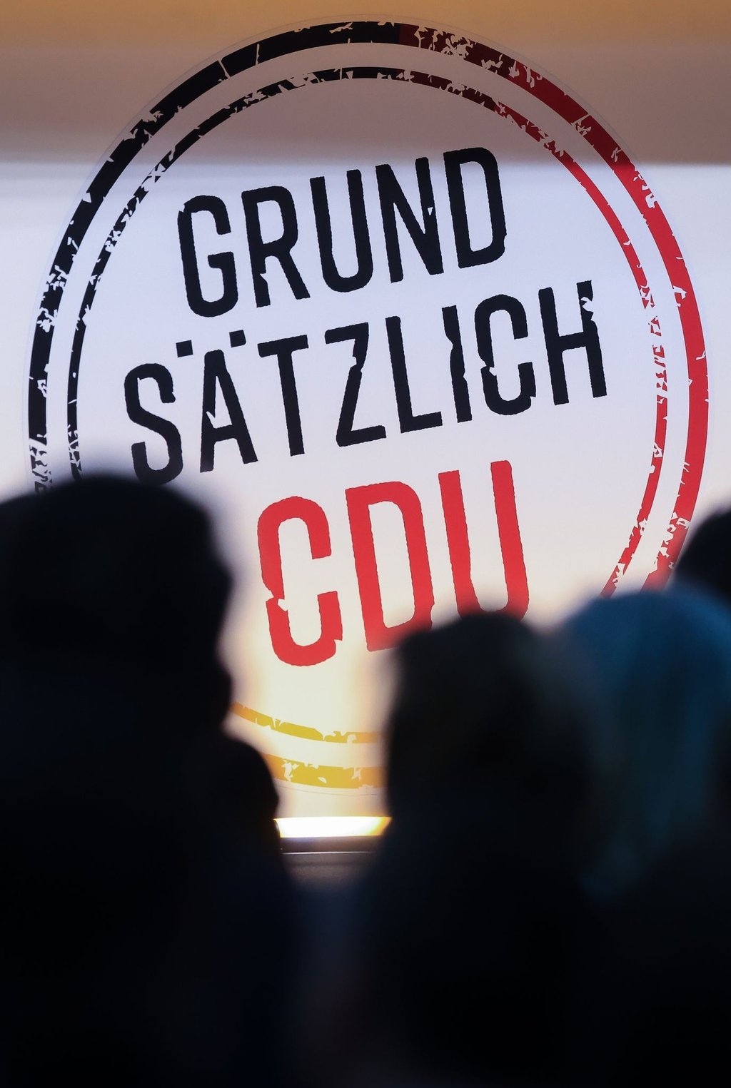 Gäste sitzen vor Beginn der CDU-Regionalkonferenz in einer Messehalle.