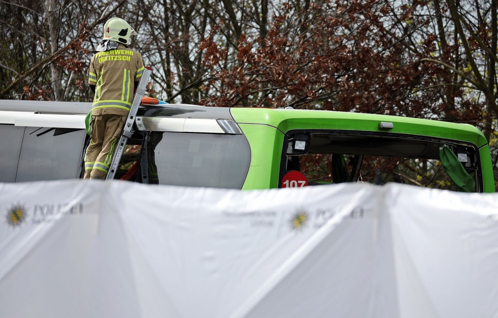 Ein Feuerwehrmann untersucht den Reisebus hinter mobilen Sichtschutzwänden an der Unfallstelle auf der A9.