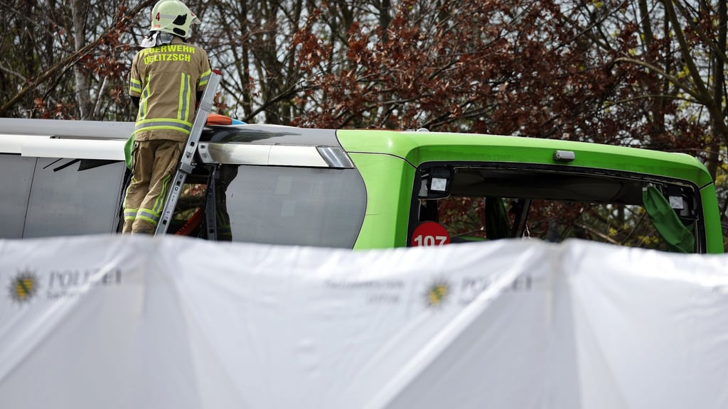 Ein Feuerwehrmann untersucht den Reisebus hinter mobilen Sichtschutzwänden an der Unfallstelle auf der A9.