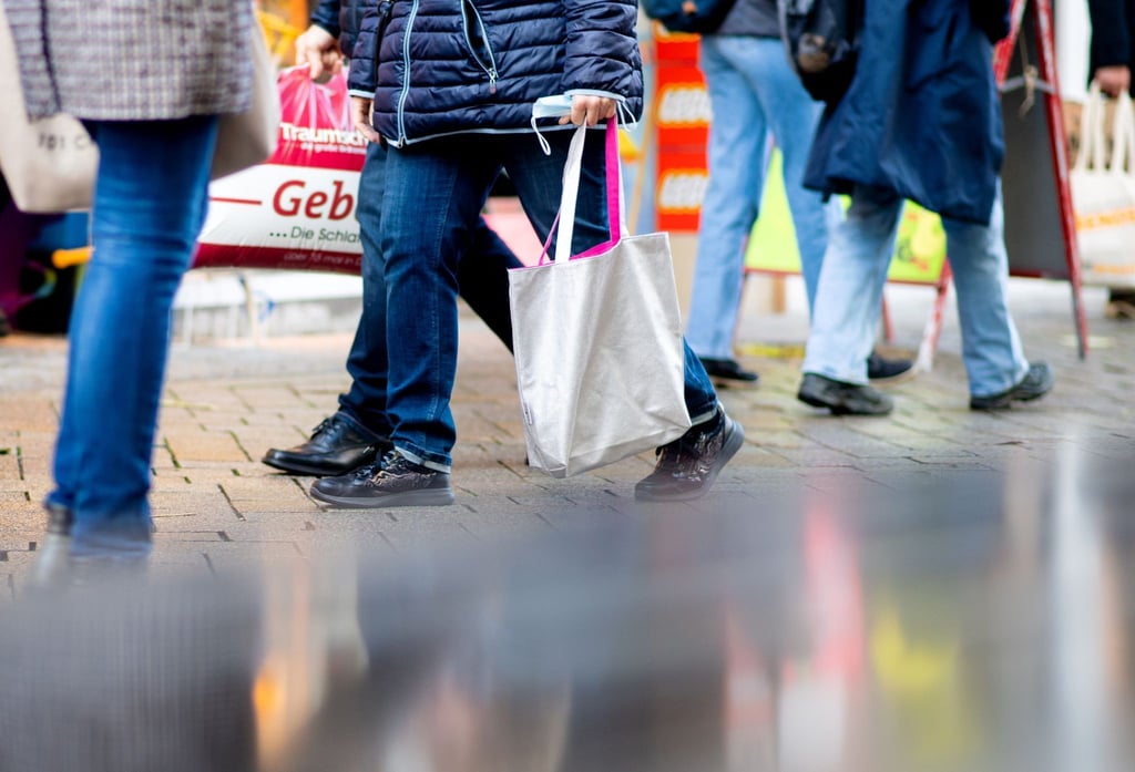 Menschen gehen an einem verkaufsoffenen Sonntag mit Einkaufstaschen durch die Fußgängerzone der Innenstadt.