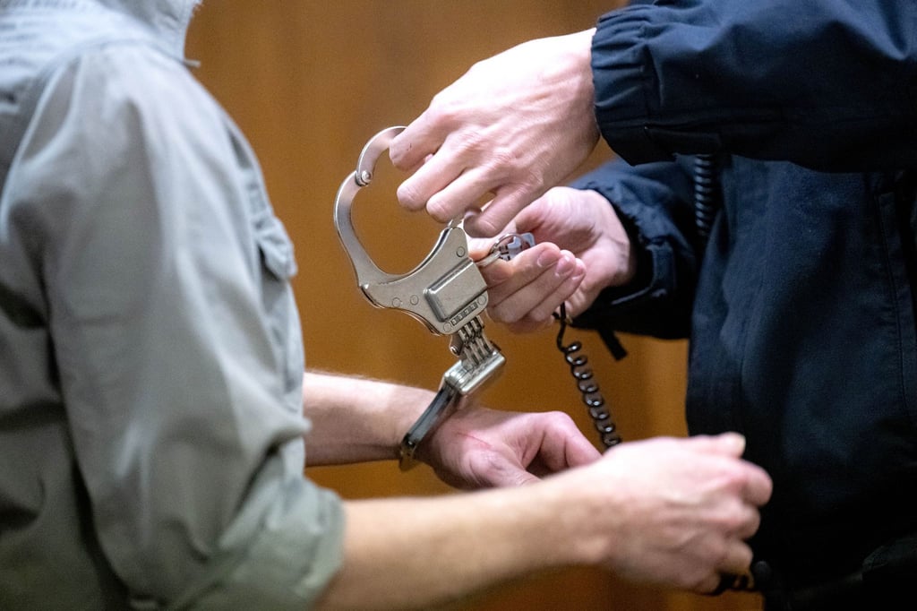 Der Angeklagte (l) wird in den Gerichtssaal im Landgericht geführt.