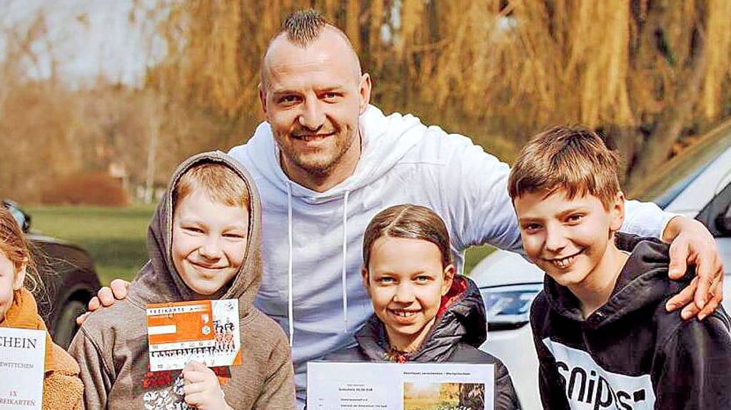 Toni Lindenhahn mit Kindern, die Gutscheine zeigen.