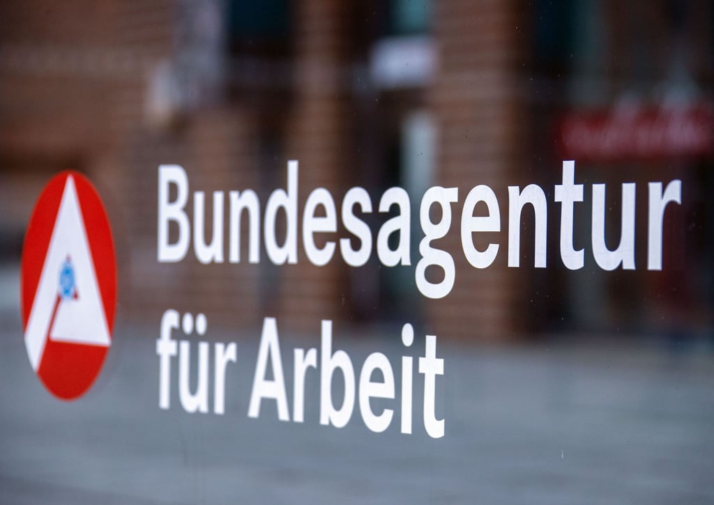 Das Hinweisschild für die Bundesagentur für Arbeit ist an einer Glasfläche vor einem Bürogebäude zu sehen.