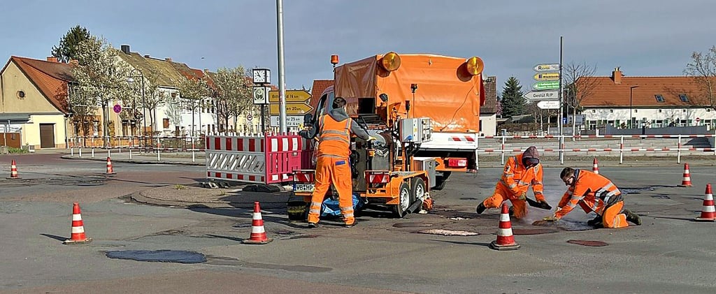 Mitarbeiter der Straßenmeisterei Sandersdorf legen Hand mit heißem Bitumen an und füllen die Löcher auf dem Zörbiger Kreisel.