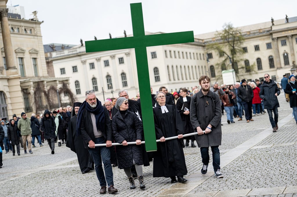 Gläubige tragen bei der Karfreitagsprozession der St. Marienkirche ein grünes Kreuz über den Bebelplatz.