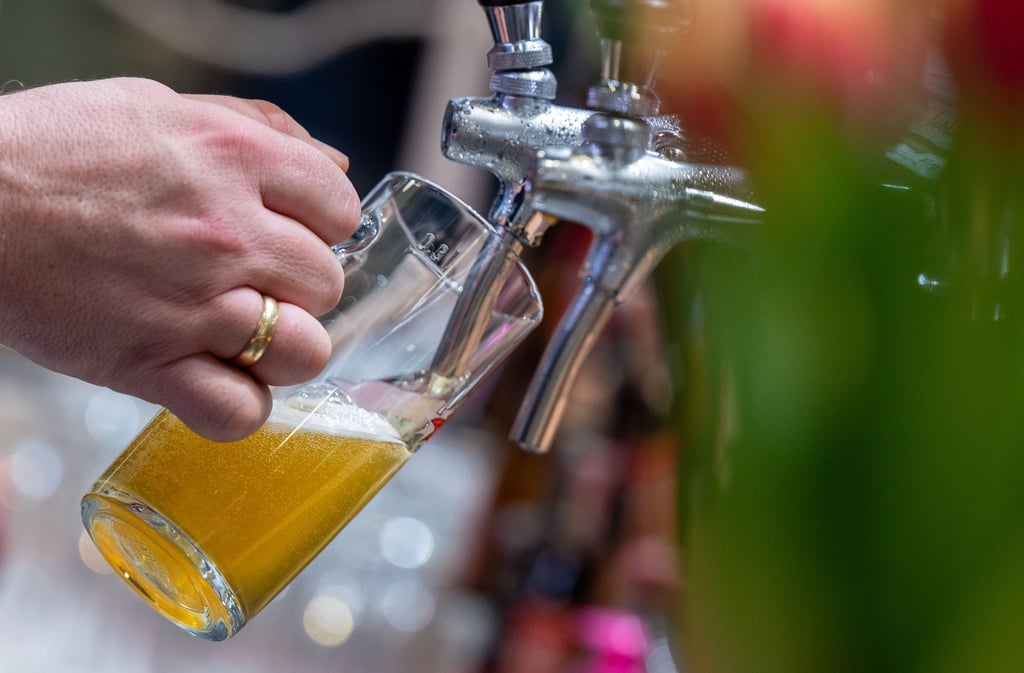 Ein Mann gießt Bier vom Zapfhahn ins Glas.