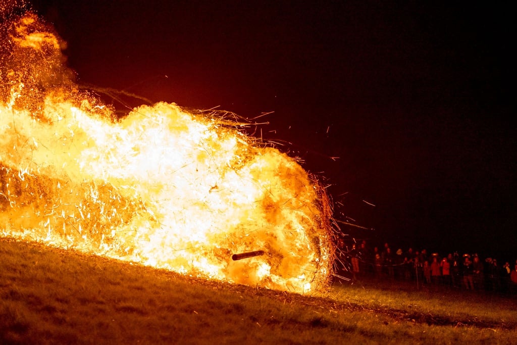 Ein brennendes Holzrad rollt den Osterberg hinunter in Richtung der Ortschaft Lügde beim jährlichen Osterräderlauf.