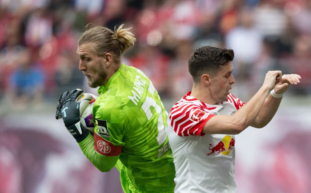 Leipzigs Christoph Baumgartner (r) und der Mainzer Torhüter Robin Zentner kämpfen um den Ball.