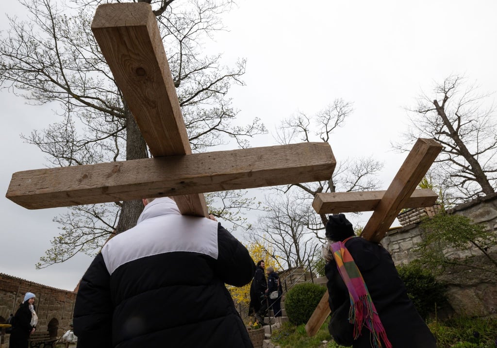 Menschen tragen Holzkreuze auf dem ökumenischen Kreuzweg.