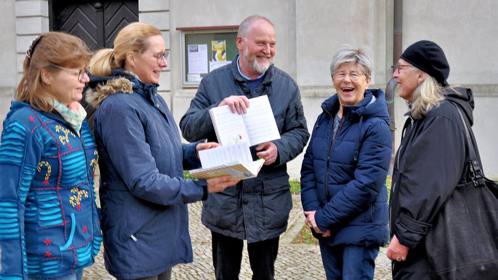 Fröhliche Runde: Kantor Gottfried Spiegel präsentiert eine Liedauswahl für das offene Singen. Beate Gohr (2. v. li.) hatte die Idee zu der Aktion.