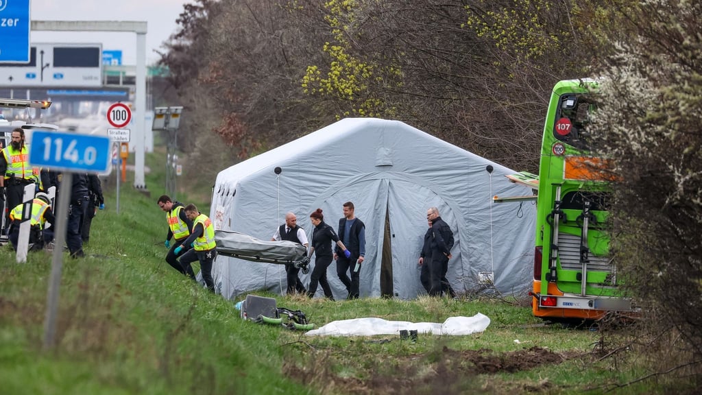 Bestatter tragen ein Todesopfer des verunglückten Flixbusses von der Unfallstelle auf der A9.
