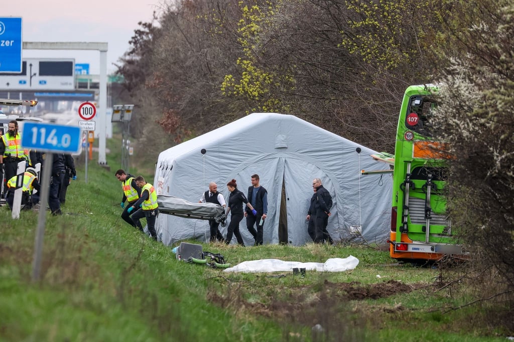 Bestatter tragen ein Todesopfer des verunglückten Busses von der Unfallstelle auf der A9.