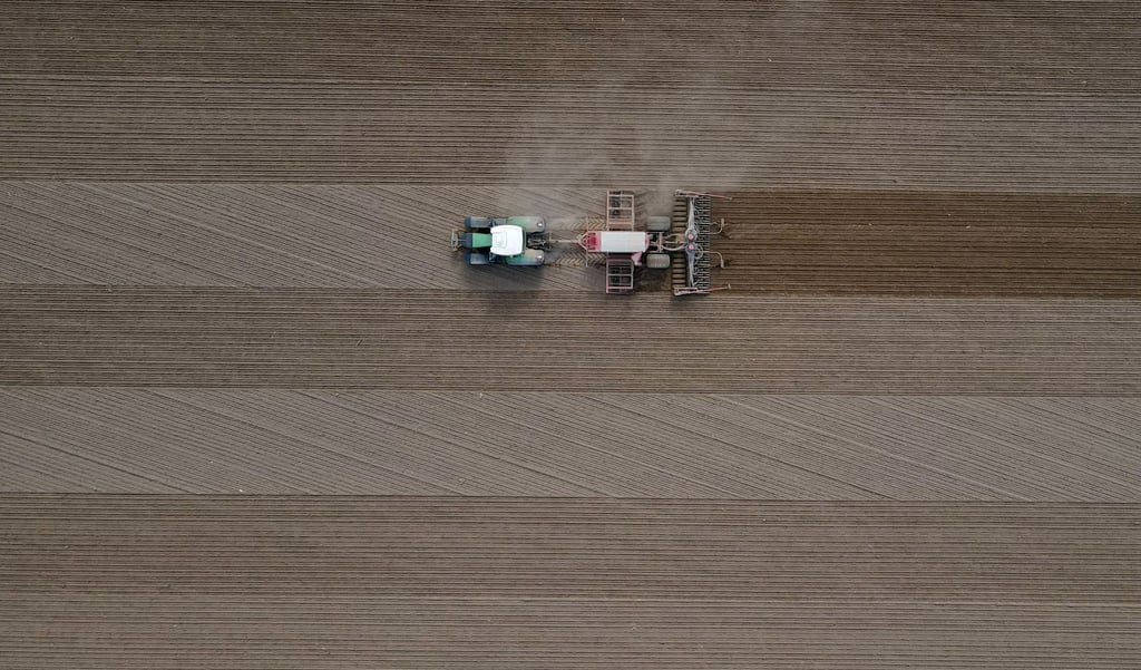 Ein Landwirt fährt mit seinem Traktor über ein Feld und bringt Saatgut in den Boden aus.