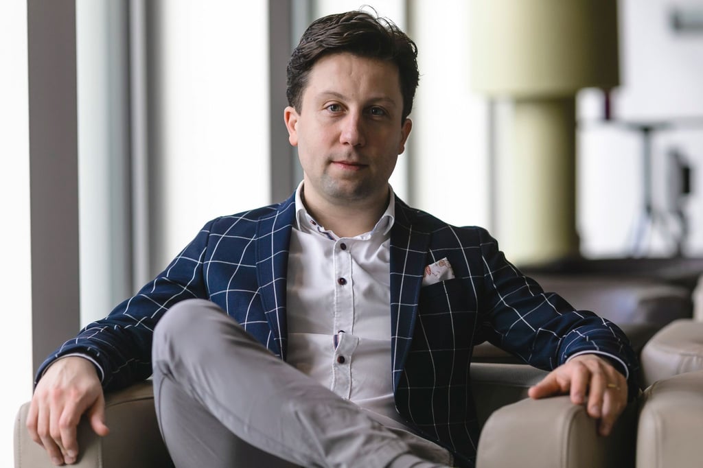 Der neue Generalmusikdirektor des Theaters Kiel, Benjamin Reiners, sitzt in der Lobby eines Hotels.