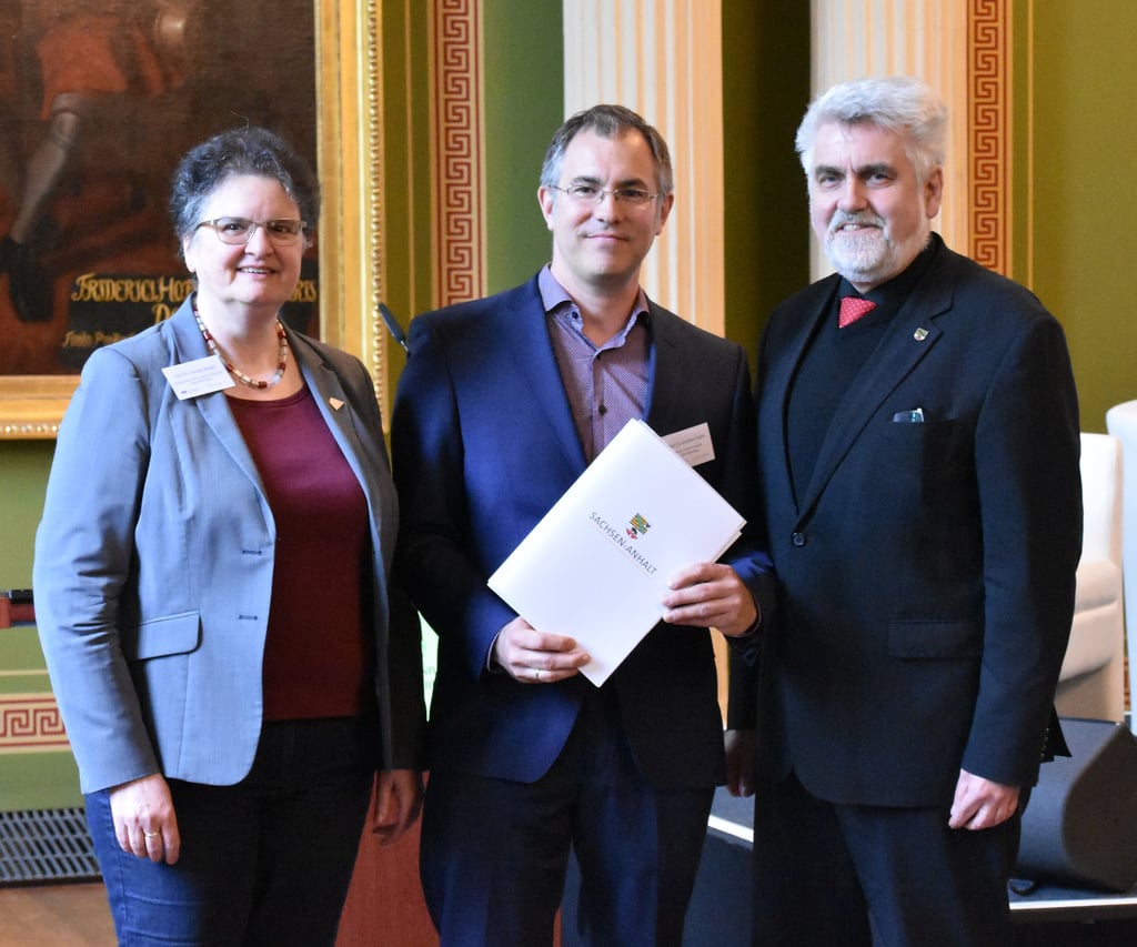 Minister Armin Willingmann (r.) übergibt einen Förderbescheid an Uni-Rektorin Claudia Becker und Wissenschaftler Jonathan Everts.
