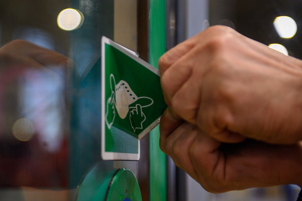Ein Mitarbeiter der MVB entfernt einen Maskenpflicht-Aufkleber von der Tür einer Straßenbahn.