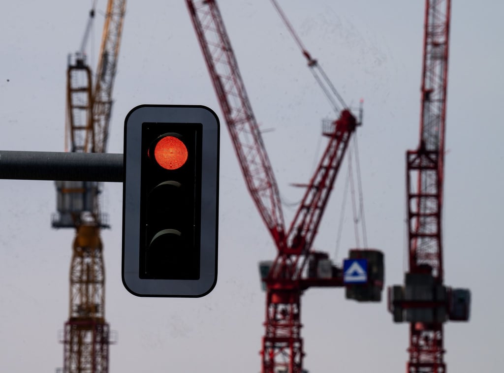 Eine Rot zeigende Ampel vor der Kulisse von Kränen auf einer Baustelle am Alexanderplatz.