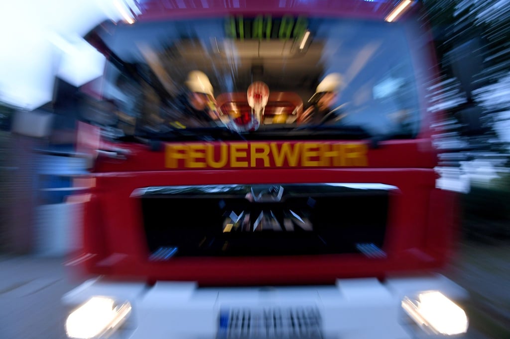 Einsatzkräfte der Feuerwehr sitzen in ihrem Fahrzeug.