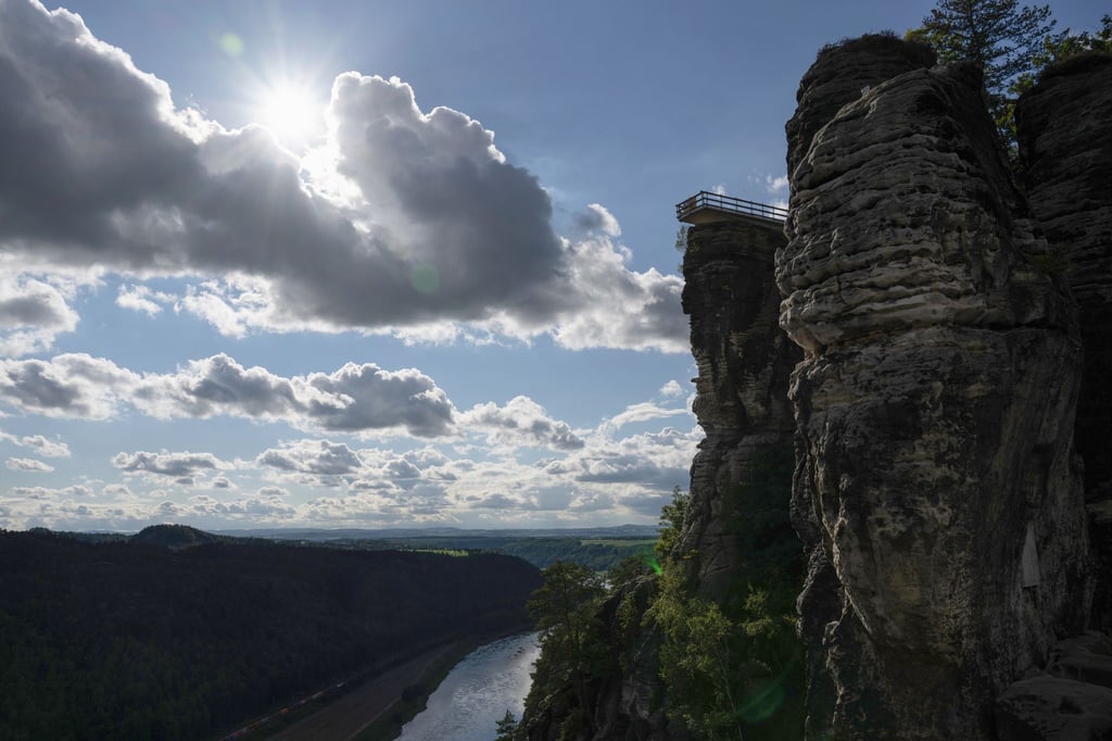 Der neue Aussichtssteg der Bastei zeichnet sich im Elbsandsteingebirge im Nationalpark Sächsische Schweiz im Gegenlicht der Sonne als Silhouette ab.