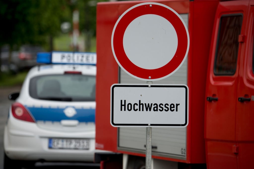 Ein Schild mit der Aufschrift "Hochwasser" steht während des Hochwassers der Weißen Elster auf einer Zufahrtsstraße.