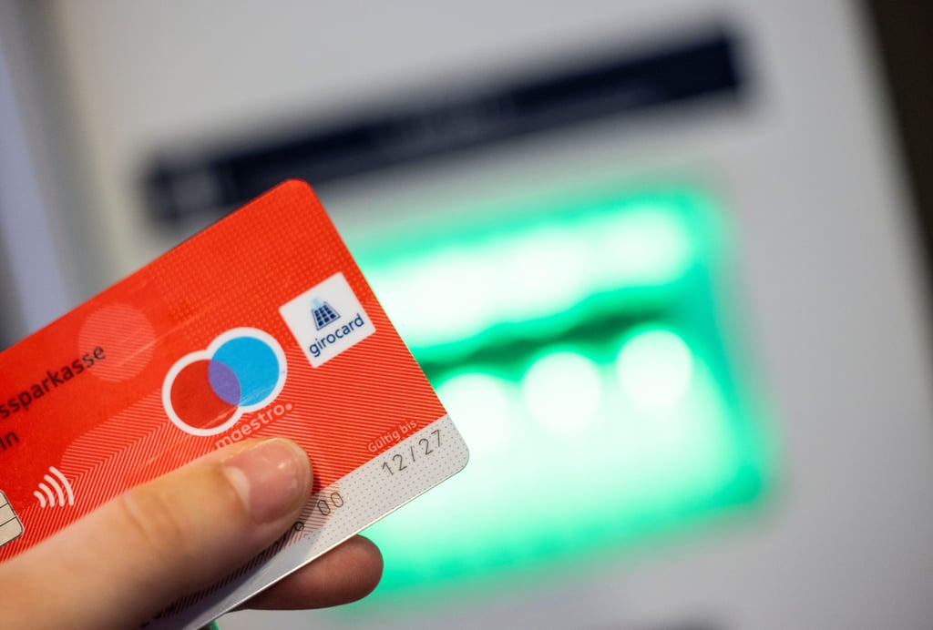 Eine Bankkundin verwendet ihre Girokarte, um Bargeld an einem Geldautomaten abzuheben. Kunden mehrerer Banken haben am Donnerstag Probleme beim bargeldlosen Bezahlen gemeldet.