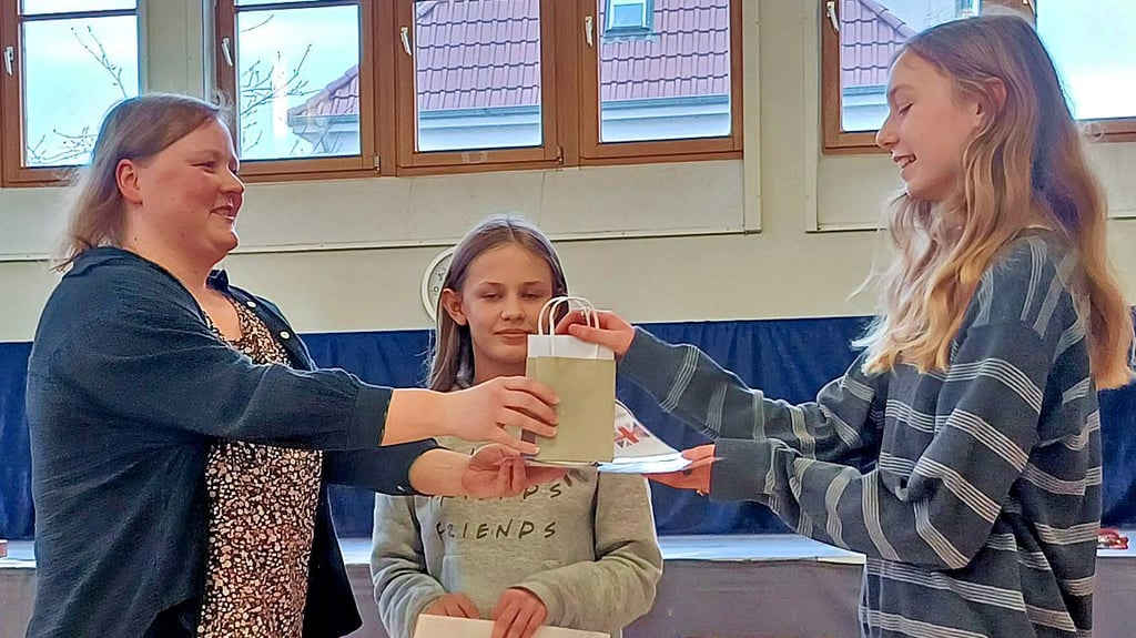 Gymnasiasten erhalten für ihre Leistung bei der Olympiade im Fach Englisch jeweils eine Urkunde und ein Geschenk.