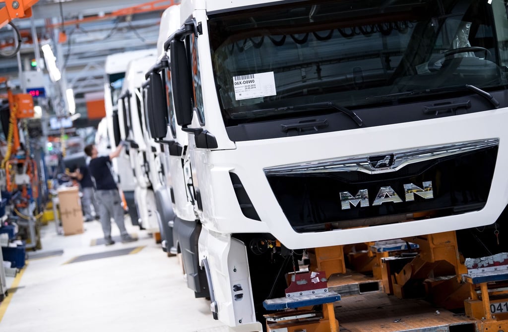 Mitarbeiter von MAN Truck & Bus arbeiten in einer Produktionsstraße.