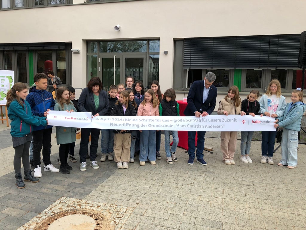 Bei der Einweihung der Hans-Christian-Andersenschule hat Bürgermeister Egbert Geier gemeinsam mit Schulleiterin Bianca Kutzener und Kindern ein Band durchgeschnitten.