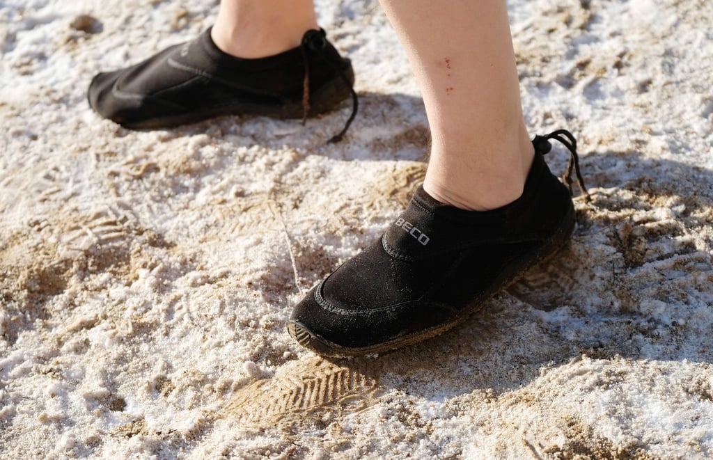 Ein Teilnehmer des Neujahrsschwimmen trägt am Ufer des Heidebades in Halle Neoprenschuhe.