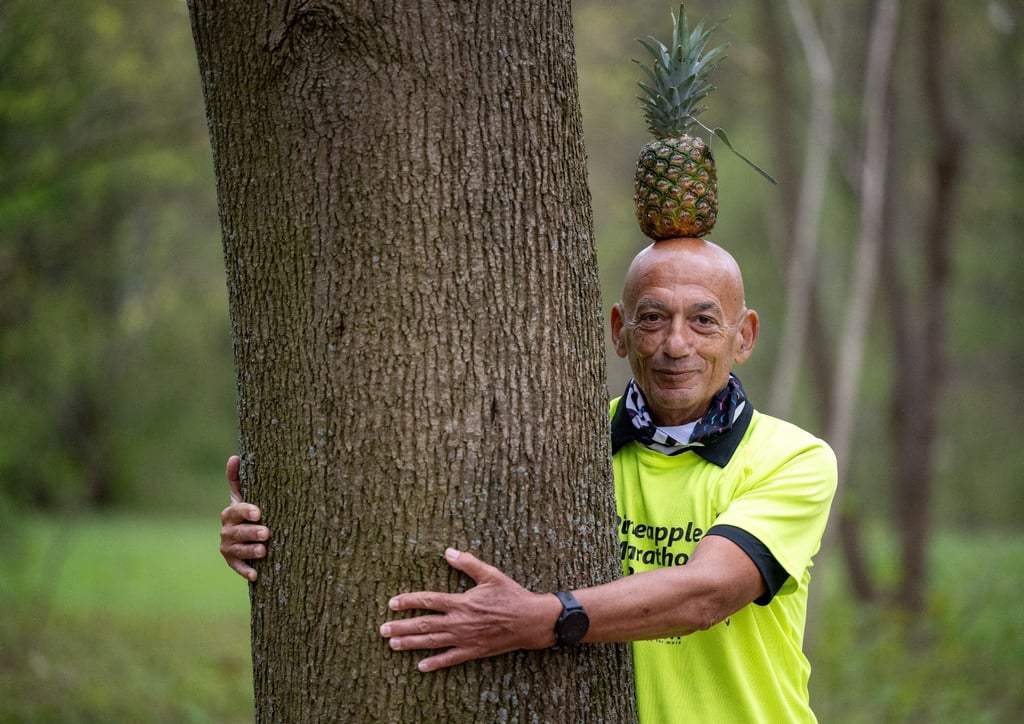 Moshe Lederfien, ein israelischer Marathon-Läufer, der bei seinen Läufen stets eine Ananas auf dem Kopf trägt, umarmt einen Baum im Tiergarten.