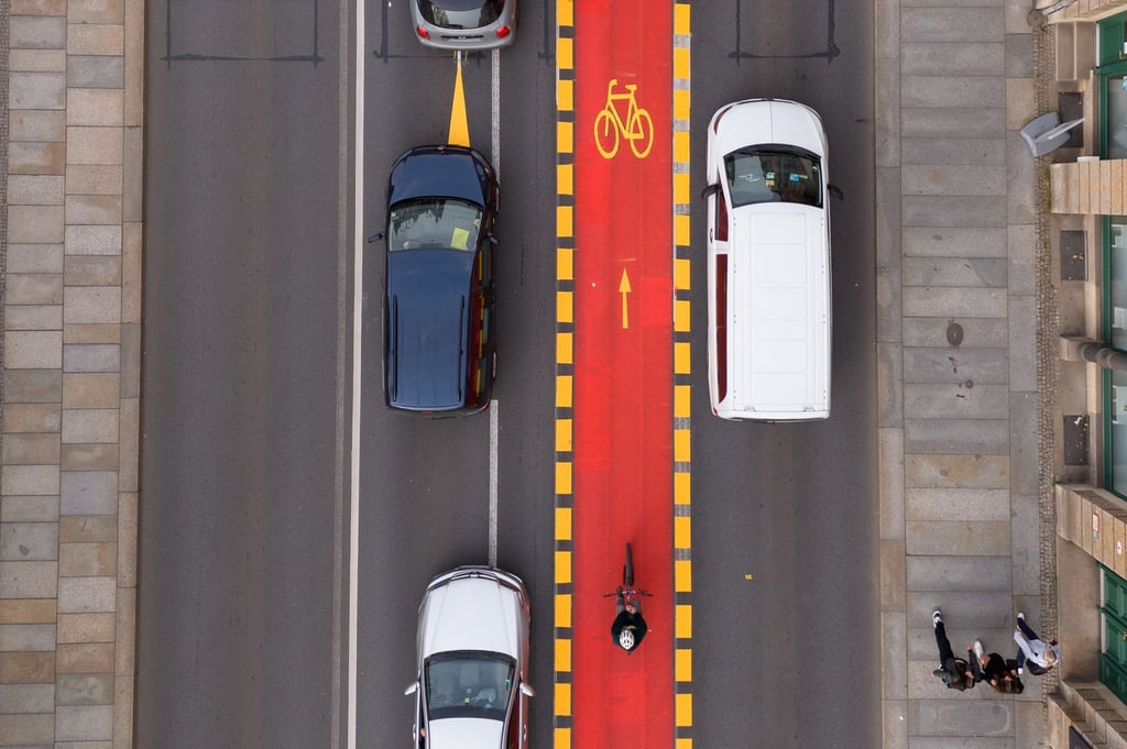 Autos stehen an der Elbbrücke Blaues Wunder an einem rot markierten Radweg.
