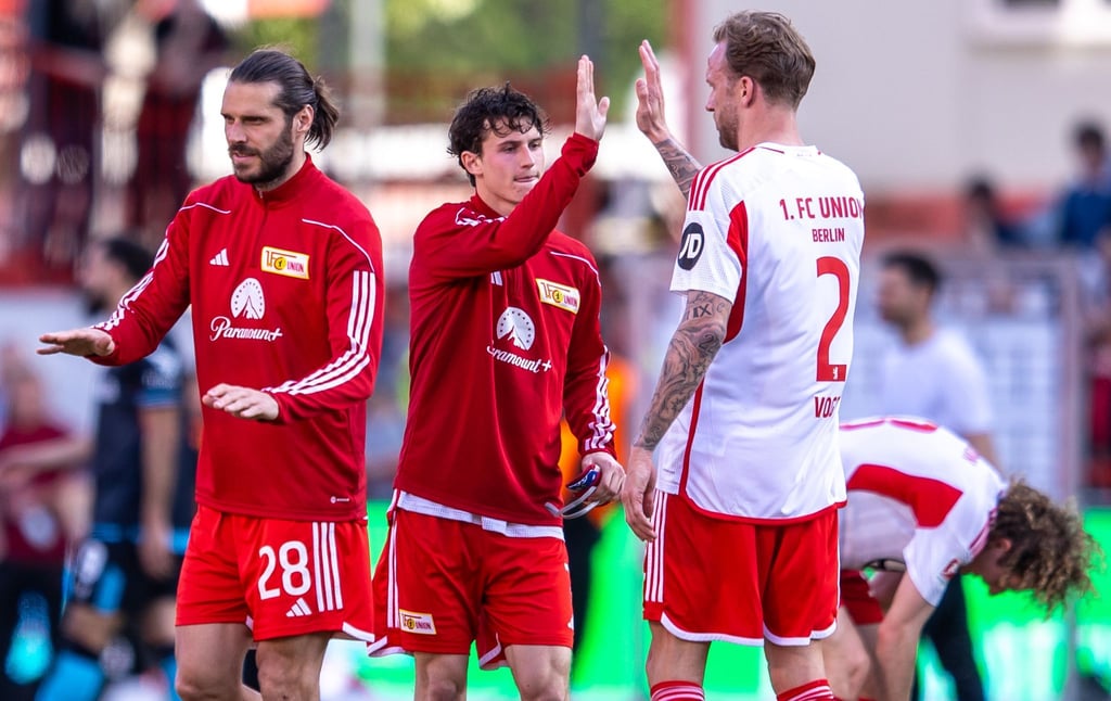 Berlins Christopher Trimmel (l-r), Brenden Aaronson und Kevin Vogt klatschen sich nach dem Spiel ab.