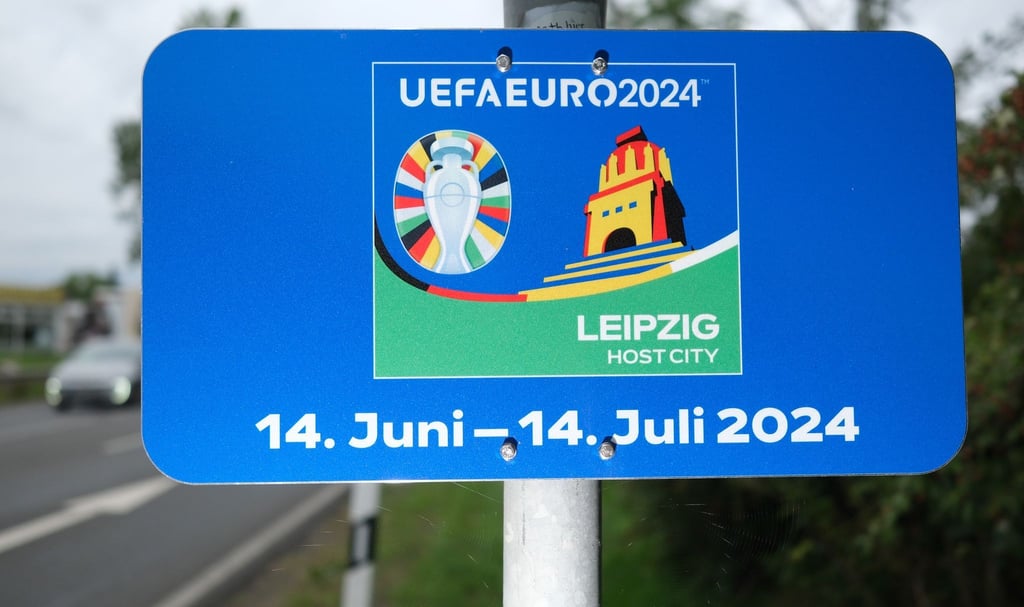 Eine Tafel zur kommenden Fußball-EM ist ergänzend am Ortseingangsschild angebracht. Leipzig ist einer der Austragungsortes des Turnieres.